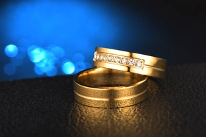 Macro shot of gold stainless steel couple rings with cubic zirconia on black leather