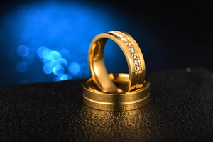 Macro shot of polished gold-plated stainless steel couple rings with zircon pavé setting