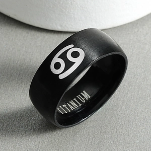 Detail of matte black titanium ring showing brushed texture and Cancer zodiac symbol