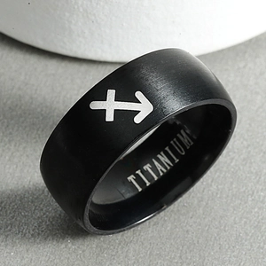 Macro view of Sagittarius zodiac symbol engraved on black brushed titanium ring surface