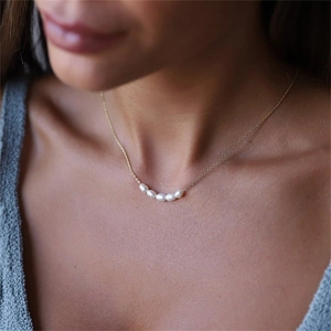 Collier élégant avec cinq perles d'eau douce blanches sur une fine chaîne en acier doré