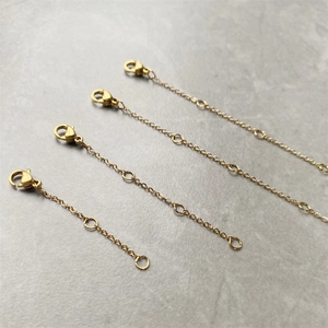 Close-up of four gold stainless steel extender chains with lobster clasps for jewelry
