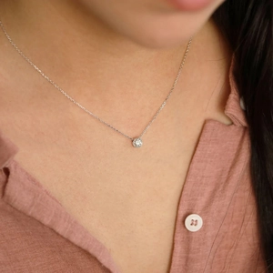Detailed view of a minimalist round zircon pendant on a fine silver stainless steel chain