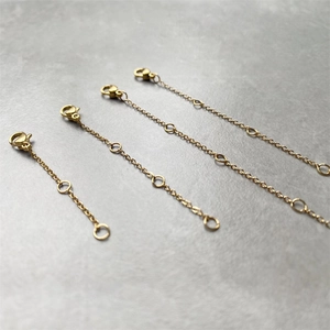 Detailed macro view of four gold-plated stainless steel extender chains with lobster clasps