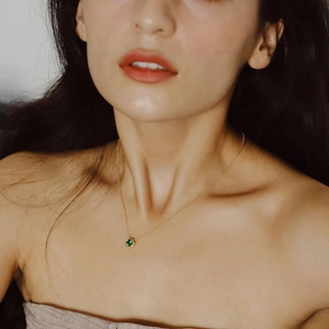 Élégant collier en or avec un pendentif rond en pierre verte porté sur le cou d'un modèle