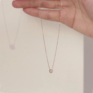 Détail d'un pendentif en or rose serti d'un cristal rond sur une chaîne à mailles fine