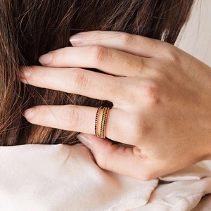 Detailed close-up of three stacked 14K gold-plated rings with colorful gemstones