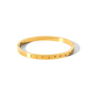 Close-up of gold stainless steel bangle with star engraving and cubic zirconia detail