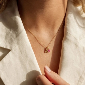 Dettaglio di una collana zodiacale d'oro con gemma rosa e pendente del Leone