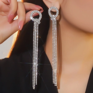 Dettaglio di orecchini pendenti in argento con nappe di strass e catene di cristallo