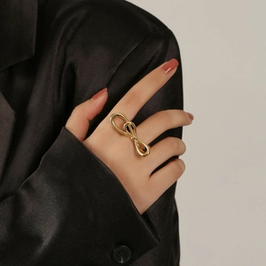Gros plan d'une bague nœud évidée plaquée or 18 carats au doigt avec un blazer noir