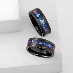 Faceted black titanium ring with galaxy opal inlay on minimalist white background