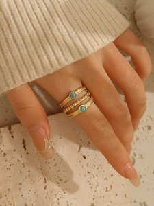 Dettaglio di tre anelli impilabili placcati in oro 18k con turchese su una modella