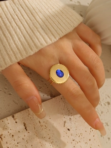 Dettaglio macro di un anello vintage placcato oro 18k con trama a raggiera e pietra blu
