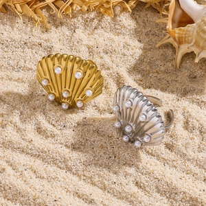Anelli a conchiglia regolabili con perle in oro e argento su una spiaggia sabbiosa