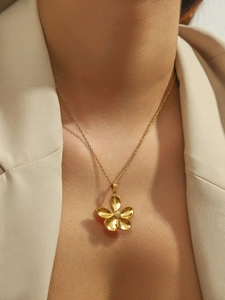 Close-up of a gold stainless steel five-petal flower pendant necklace on a model