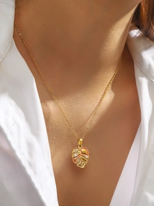 Macro detail of leaf pendant with pink enamel and crystals on gold chain necklace