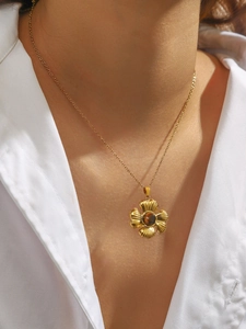 Detail of gold flower necklace with tiger eye stone worn on model with white shirt