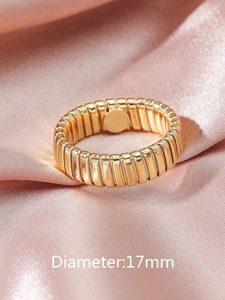 Macro detail of gold-plated ribbed Tubogas style ring on pink satin fabric background