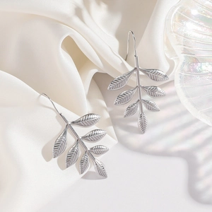 Elegant silver stainless steel leaf-shaped drop earrings displayed on silk background