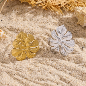 Bladvormige roestvrijstalen ringen in goud en zilver op zand voor een zomerse look