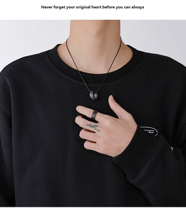 Close-up of minimalist matte black stainless steel ring and matching cylinder necklace