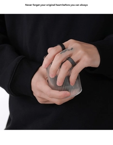 Detailed shot of two minimalist matte black ceramic rings held against a glass