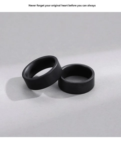 Close-up of minimalist black matte rings with a smooth brushed finish on grey background