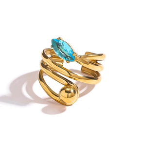 Détail macro d'une bague spirale plaquée or 18k avec pierre bleue marquise et bille polie