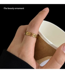 Close-up of a gold coin-shaped ring worn on finger with a vintage cultural design