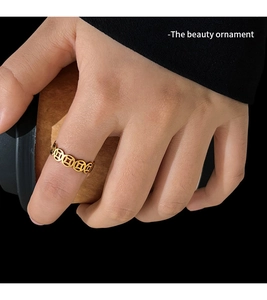 Detail of a gold coin pattern ring shown in a stylish lifestyle setting on a hand