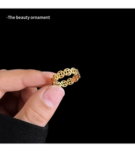Detailed close-up of golden ring with hollow Chinese coin patterns and polished finish