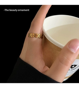 Macro detail of golden chain ring with traditional Chinese coin motifs on model finger