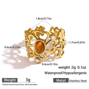 Macro shot of gold stainless steel ring featuring amber stone and clover cutout details