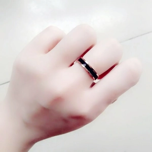 Detail view of a rose gold ring with a black ceramic inlay worn on a hand