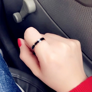Close-up of rose gold and black ceramic titanium ring on finger with modern car interior background