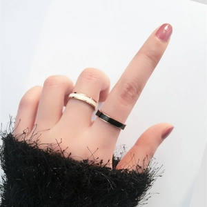 Detail of rose gold rings with black and white enamel drip on hand with dark sleeve