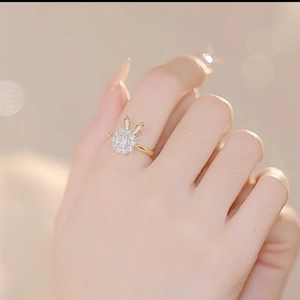 Detailopname van een roterende gouden konijnenring met glinsterende steentjes op de vinger