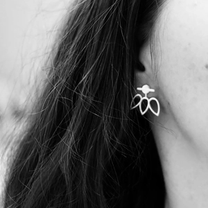 Macro shot of minimalist stainless steel hollow leaf stud earring on model ear