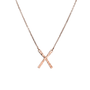 Detail view of rose gold X pendant with hammered metal texture on cross chain