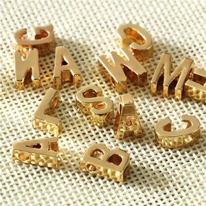 Macro shot of gold stainless steel alphabet charms with side holes for DIY jewelry