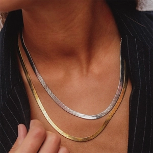 Platte visgraat ketting set in goud en zilveren afwerking gedragen op donker pak