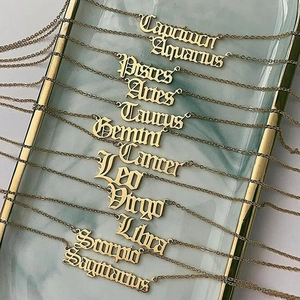 Collection of twelve zodiac pendant necklaces in gothic font on a marble display tray