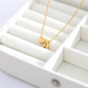 Dettaglio della collana d'oro in acciaio con ciondoli a cuore e lettera A su velluto