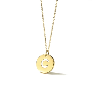 Close-up of a gold-plated circular pendant with a hollow letter C and hammered edges