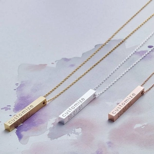 Three custom engraved bar necklaces in gold, silver, and rose gold on a gray background