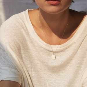 Minimalistische goldene Edelstahlkette mit ovalem Anhänger an einem Model
