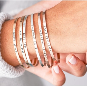 Detailed view of custom engraved stainless steel open bangles on a woman's wrist