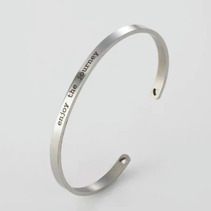 Polished silver stainless steel open heart bangle with 'enjoy the journey' engraving