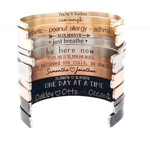 Détail de bracelets joncs empilés en acier inoxydable avec gravures personnalisées variées